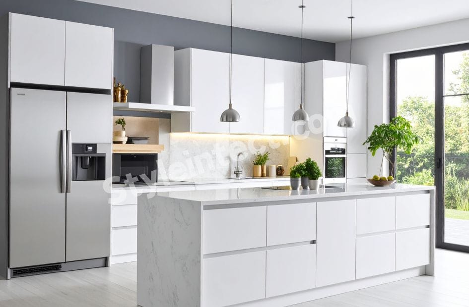 Modern Modular Kitchen Design with white handleless cabinets, marble-look waterfall island, built-in appliances, pendant lighting, and contemporary kitchen interior by StyleIntect.